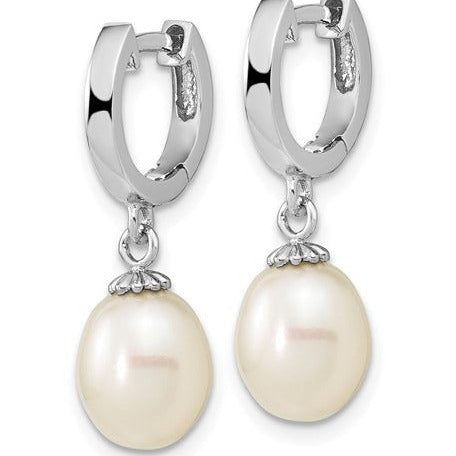 A pair of silver huggie hoop earrings with dangling freshwater pearls, shown on a plain white background.