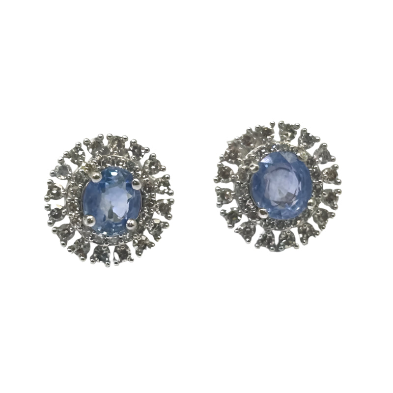 A pair of white gold earrings featuring central sapphire stones with diamond accents around them.