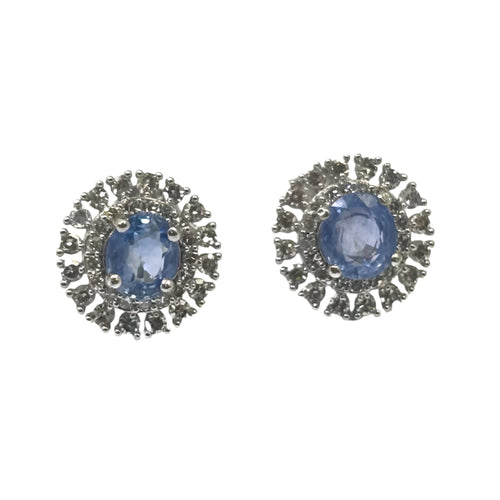 A pair of white gold earrings featuring central sapphire stones with diamond accents around them.
